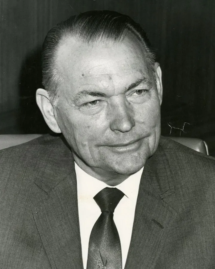 A man wearing a suit and tie smiling at the camera