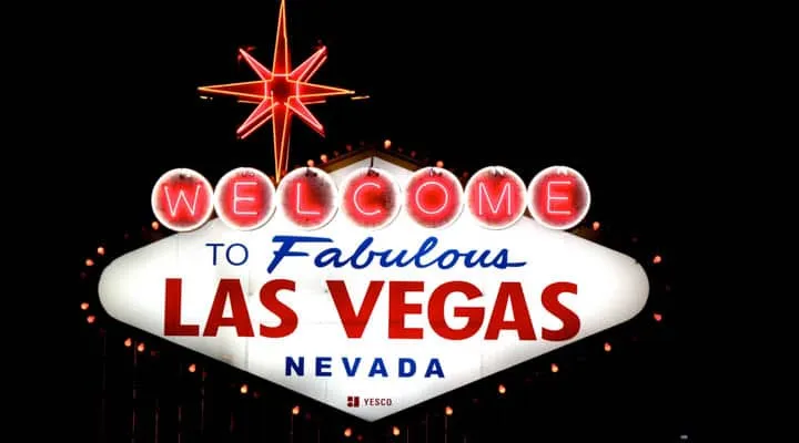 A close up of a sign with Welcome to Fabulous Las Vegas sign in the background