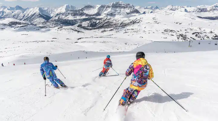 A group of people riding skis down a snow covered slope